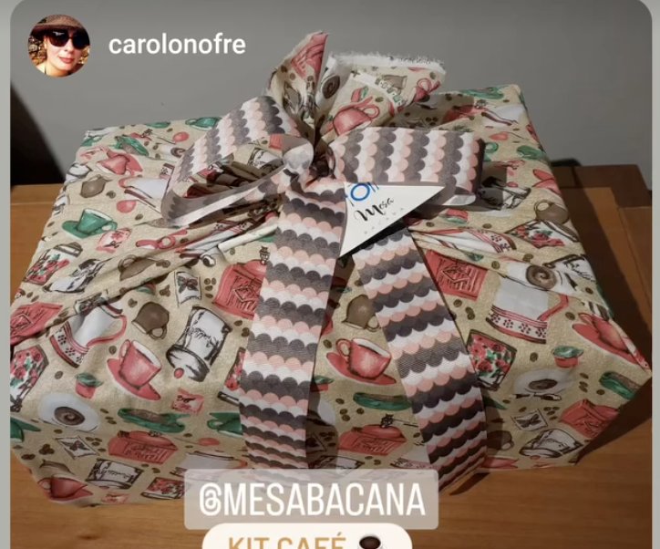 Caixa embrulhada em tecido estampado de xícaras e bules, com fita listrada