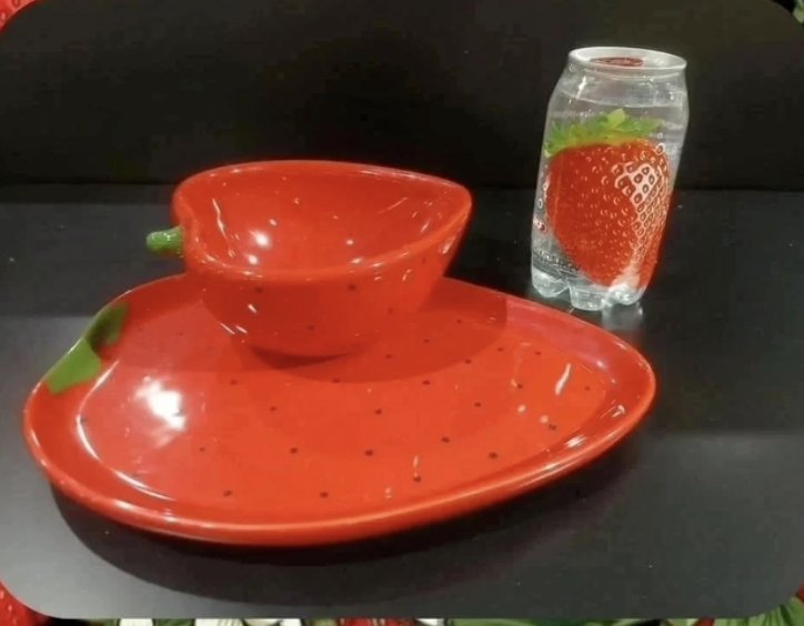 Prato e bowl vermelhos em forma de morango ao lado do refrigerante