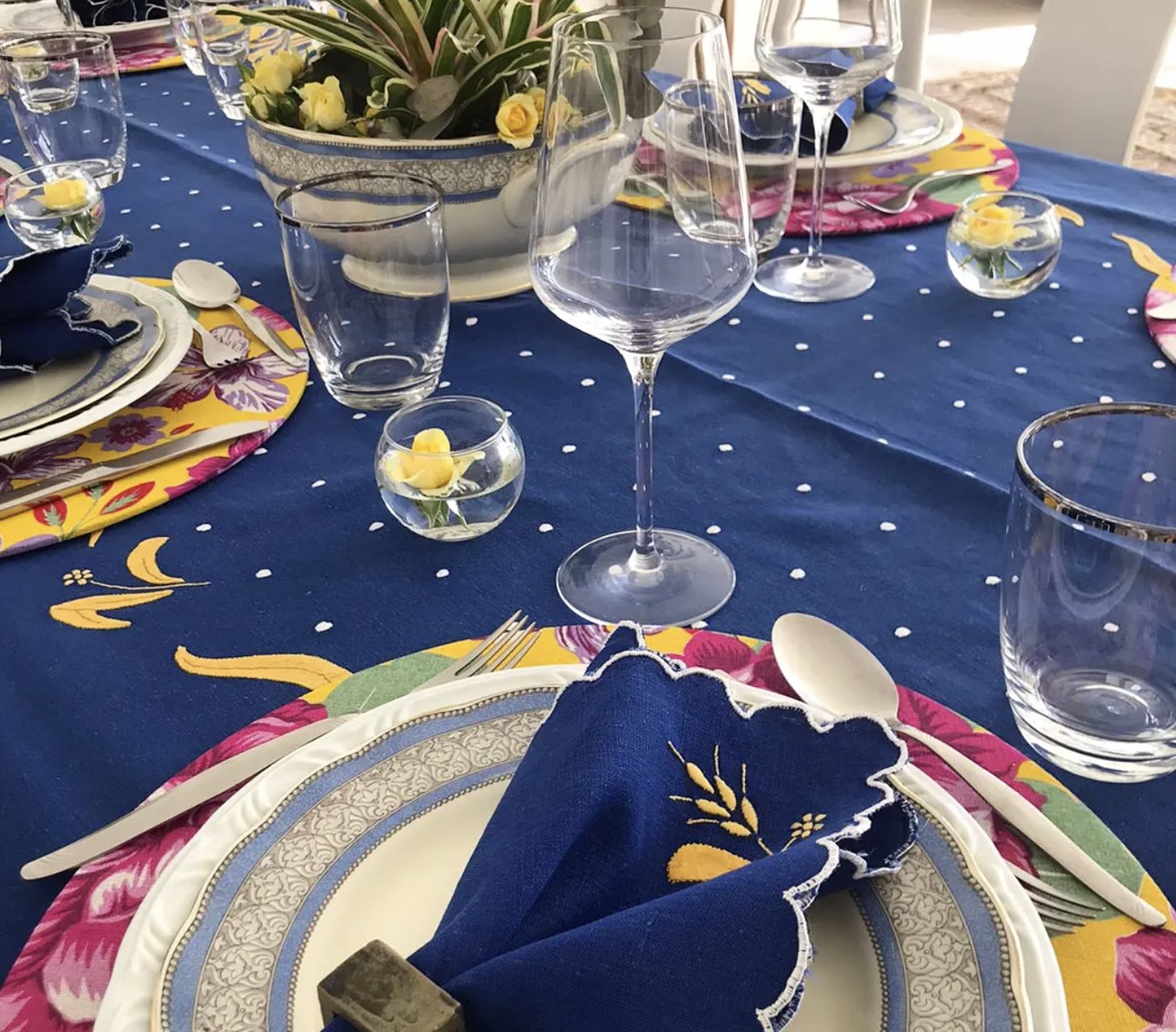 Detalhe de um lugar com taças, prato azul e guardanapo bordado