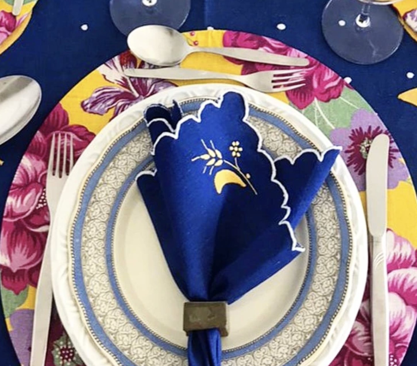 Guardanapo azul bordado com argola sobre prato de borda azul